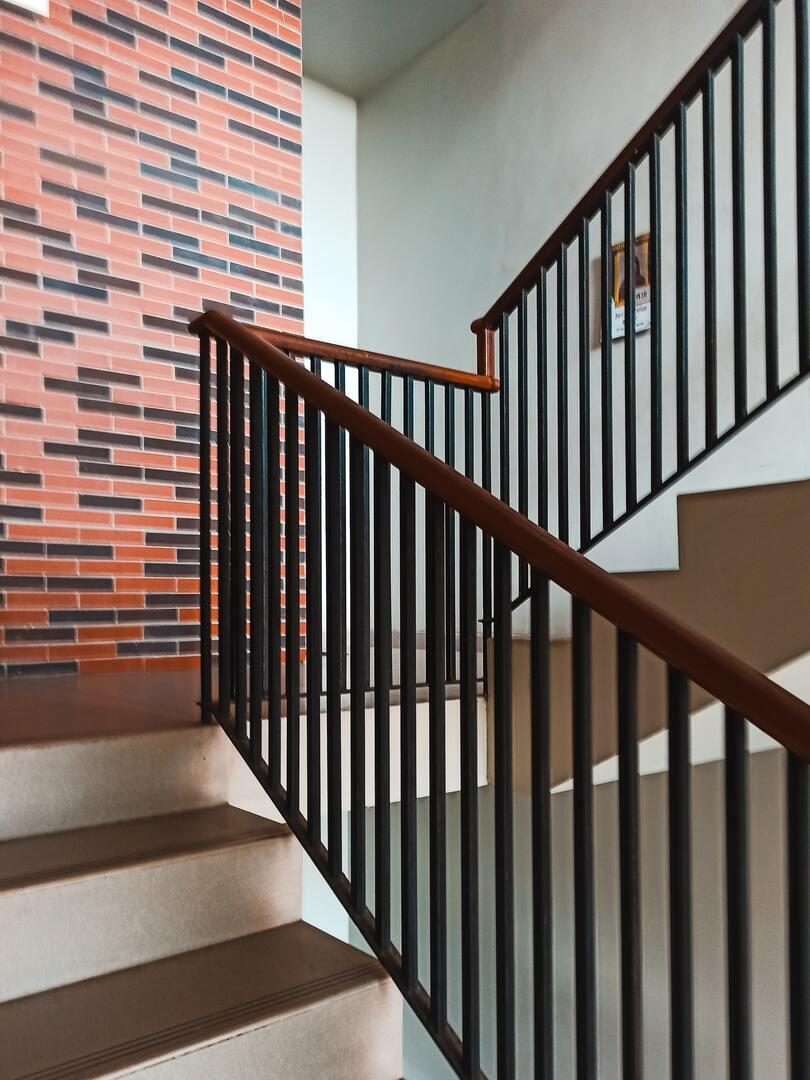 Cage d'escalier intérieure avec mur de brique multicolore et rampe métallique noire